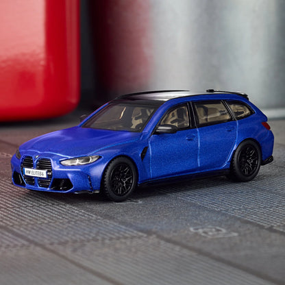 Blue model car on a metallic surface with a blurred red object in the background